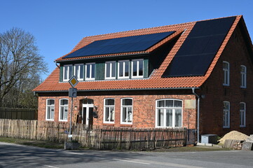 Sanierter Altbau aus roten Ziegelsteinen mit Solarpanelen auf dem Dach