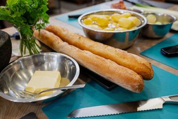 French baguettes, butter and peeled potatoes in kitchen for preparation of delicious meal