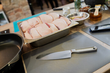 Raw duck breasts prepared for cooking on chefs kitchen with knifes and different ingredient foods