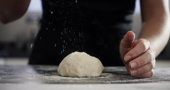 Person, hands and dough with baking on kitchen counter for flour, cooking or pizza process in apartment. Chef, bakery and pastry for recipe, handmade cake or bread with wheat or preparation in home