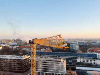 high angle close view of the jib of a yellow Tower crane on a construction site of a building.