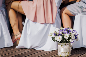 A beautiful bouquet of flowers in a paper vase stands on a wooden floor outdoors with a background...