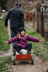 A strong man, father, grandfather rides, carries on a rusty old cart, wagon along the road in the...