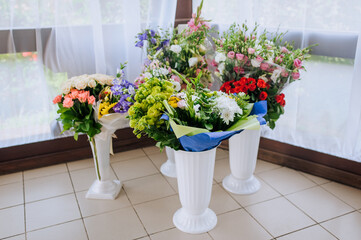 Fototapeta na wymiar Plastic white vases with many fresh colorful flowers in packages stand in the restaurant. Photography, birthday gifts, holiday concept.