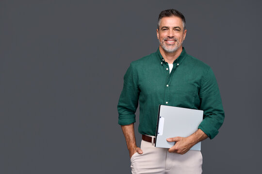 Happy middle aged business man company manager, smiling older professional salesman wearing green shirt holding pad presenting products or services ads standing isolated on gray background, portrait.