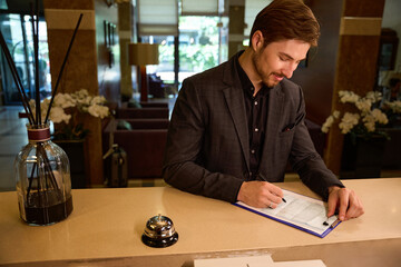 Cropped photo of young businessman filling registration form at hotel