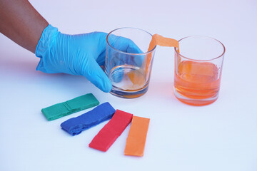 Hand wear blue glove, hold glass of color paper strip to absorb water to another glass. Concept,...