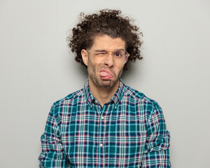 funny casual guy with curly hair and glasses making faces - obrazy, fototapety, plakaty