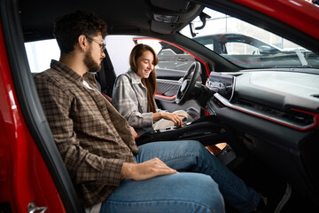 Car owners couple sit in new auto in dealership man and woman buying automobile