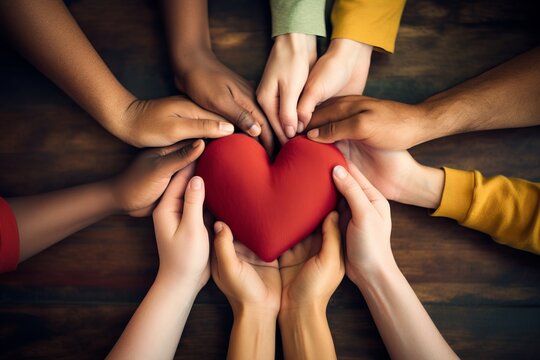 Conceptual image of hands forming a heart around a diverse group, symbolizing unity and understanding