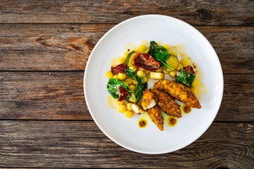 Fried chicken breast fillet with gnocchi and sun dried tomatoes on wooden table