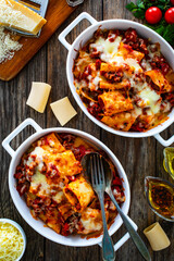 Paccheri con ragù alla bolognese casserole  - roasted noodles with bolognese  sauce and mozzarella cheese  on wooden table