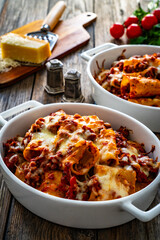 Paccheri con ragù alla bolognese casserole  - roasted noodles with bolognese  sauce and mozzarella cheese  on wooden table