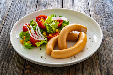 Breakfast - boiled sausages and fresh vegetables served on wooden table