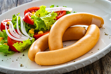 Breakfast - boiled sausages and fresh vegetables served on wooden table