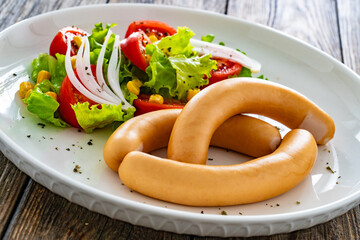 Breakfast - boiled sausages and fresh vegetables served on wooden table