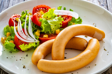 Breakfast - boiled sausages and fresh vegetables served on wooden table