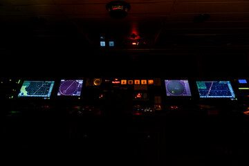Navigational bridge on big cargo ship. Wheelhouse on vessel. ECDIS, radar. Night time.