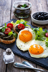 Breakfast - sunny side up egg, tapenade bruschetta and fresh vegetables on wooden table
