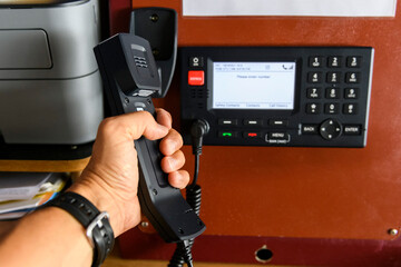 Navigational control panel and VHF radio with hand. Radio communication at sea. Working on the...