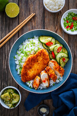 Tonkatsu - crispy Japanese pork chop with white rice and  fresh vegetables on wooden table