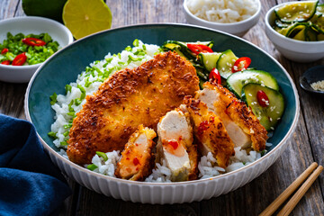 Tonkatsu - crispy Japanese pork chop with white rice and  fresh vegetables on wooden table