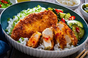 Tonkatsu - crispy Japanese pork chop with white rice and  fresh vegetables on wooden table