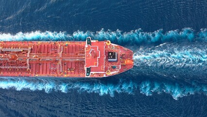 Top-down view of a crude oil tanker speeding through calm waters with trails of foam around her. Powerful diesel engine of the oil tanker roars at full speed and leaves wake water on the Ocean