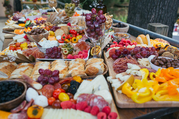 Dried fruits, fresh vegetables, slices cheeses and meats party table setup.