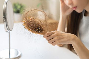 Stress asian young woman, girl hand holding comb show her hairbrush with loss, hair in brush after...