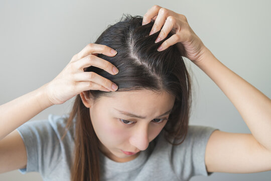 Damaged Hair symptom, face serious asian young woman, girl worry about balding, looking at scalp in mirror, hand in break into front hair loss, thin problem. Health care treatment for beauty concept.