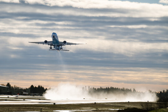 Everett, WA, USA - January 12, 2024; Boeing 777 climbs away from snow on Paine Field Everett runway in ecoDemonstrator sustainable aviation fuel livery