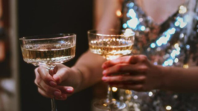 A beautiful girl holds glasses of champagne in her hands. Le coup cocktail glasses. Celebrates the New Year or a corporate holiday. Disco or retro style.