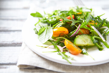 Salad with Tomatoes, Cucumber and Rocket on bright Background. Healthy Snack Idea. Close up.
