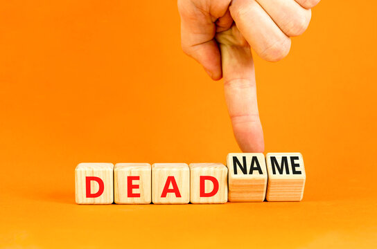 Deadname or name symbol. Concept words Deadname or Name on beautiful wooden blocks. Beautiful orange table orange background. Transgender hand. Business, deadname or name concept. Copy space.