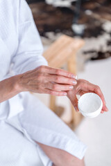 Fototapeta na wymiar Mature woman applying nourishing cream on hand skin
