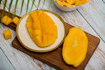 Top view of a plate with sliced juicy pulp of tropical sweet mango. Healthy fruit ripe snack of ripe mango and slices of sweet candied fruits. 