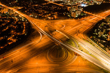 Fototapeta na wymiar Top view of car traffic at intersection lane and buildings. Long exposure of urban cityscape at night. Modern city in Canada full of night lights from energy and power.
