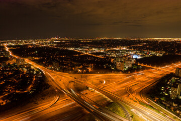 Fototapeta na wymiar Top view deep night city of car traffic at intersection lane and buildings. Long exposure of urban cityscape. Modern city life in Canada, moving cars, trucks and buses.