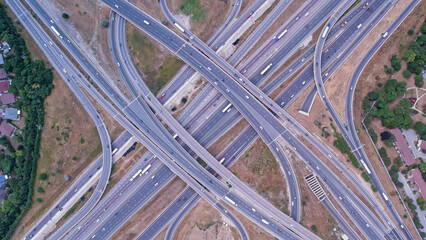 Top down aerial of cars drive across the expressway road in Canada. Cityscape and Highway. Transportation traffic at multilevel high speed road complex in North America.