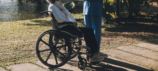 Nursing staff talking to an elderly person sitting in a wheelchair.
