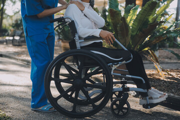 Obraz premium nurse with elderly man in wheelchair at park