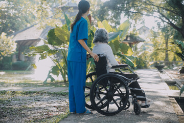 A nurse take care a senior male on wheelchair in his garden at home