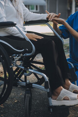 Obraz premium A nurse take care a senior male on wheelchair in his garden at home