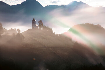 Jamnik, Slovenia - Magical foggy summer sunrise at Jamnik St.Primoz church. - obrazy, fototapety, plakaty