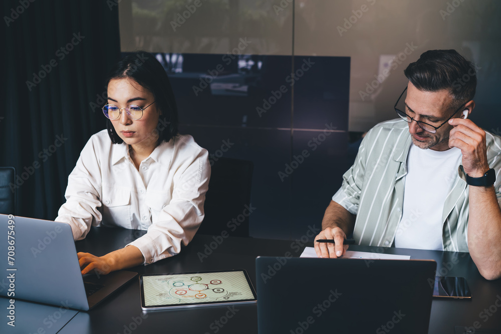 Poster male and female colleagues in optical spectacles for provide vision correction using laptop computer