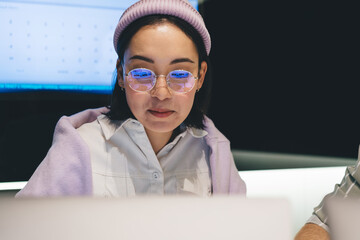 Asian female IT professional in optical spectacles for provide vision correction browsing web...