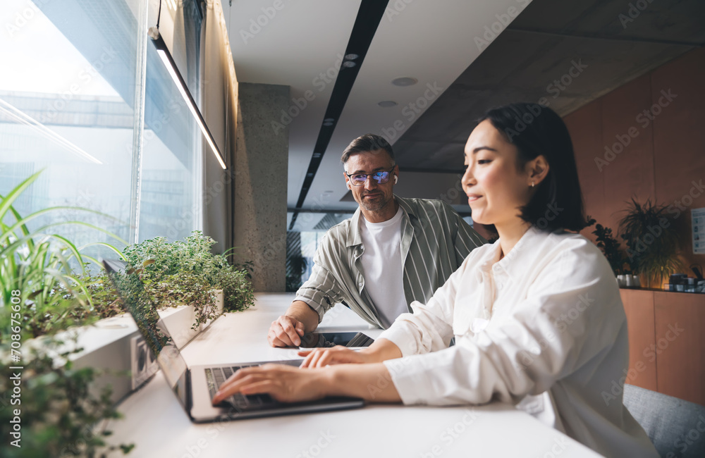 Poster skilled male and female colleagues using application on modern laptop computer for creating startup 