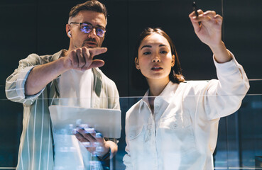 Male and female colleagues with modern touch pad technology discussing business marketing during...