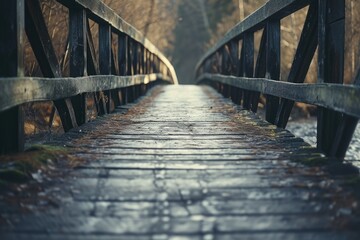 Obraz premium A wooden bridge crossing over a flowing stream of water. This picture can be used to depict nature, tranquility, and a peaceful setting